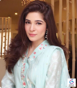 Ayesha Omar smiling in a stylish outfit during a photoshoot for her 2026 biography featuring her career, age, height, family, dramas, and net worth.