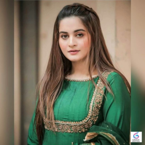 Aiman Khan smiles while wearing a stylish traditional dress in a professional photo shoot for her life story and job history.