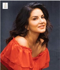Sunny Leone attending a media event in a stylish black dress, posing gracefully for photographers on the red carpet.